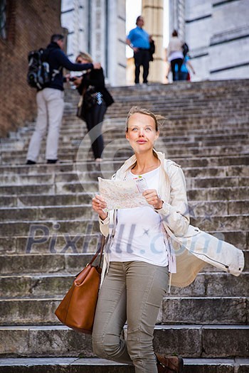 Gorgeous female tourist with a map discovering a foreign city (shallow DOF; color toned image)
