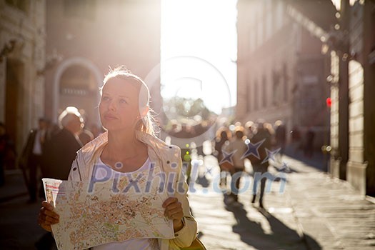Gorgeous female tourist with a map discovering a foreign city (shallow DOF; color toned image) backlit by warm evening sunshine Gorgeous female tourist with a map discovering a foreign city (shallow DOF; color toned image) backlit by warm evening sunshine