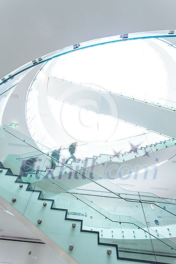 People inside a modern building walking up the stairs (color toned image; motion blurred image) People inside a modern building walking up the stairs (color toned image; motion blurred image)