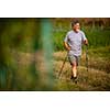 Active handsome senior man nordic walking outdoors on a forest path, enjoying his retirement