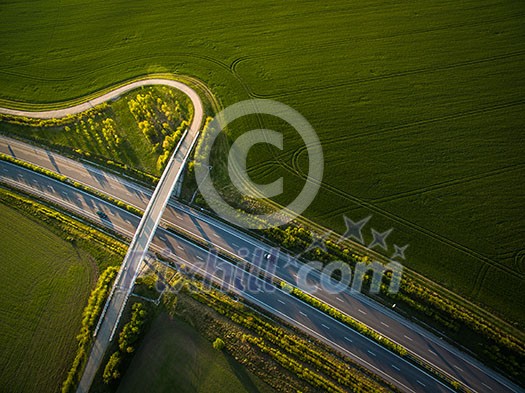 Aerial view of a highway amid fields with cars on it Aerial view of a highway amid fields with cars on it