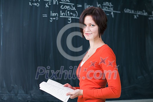 Pretty, young college student writing on the chalkboard/blackboard during a math class (color toned image) Pretty, young college student writing on the chalkboard/blackboard during a math class (color toned image)