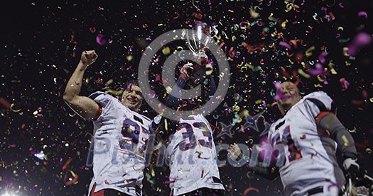happy american football team celebrating victory with trophy and confetti on the night field happy american football team celebrating victory with trophy and confetti on the night field