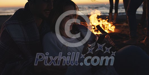 Couple using cell phone during beach party with friends drinking beer and having fun Couple using cell phone during beach party with friends drinking beer and having fun