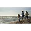 Family with kids resting and having fun at beach during autumn day
