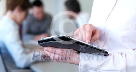 Businessman using tablet computer in office with coworkers in background Businessman using tablet computer in office with coworkers in background