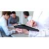 Businessman using tablet computer in office with coworkers in background