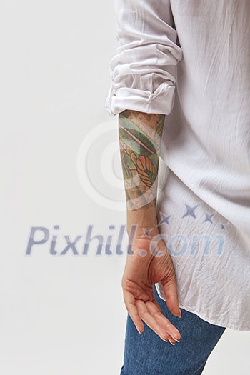 Back view of standing young woman with tattoo on hands. Isolated on gray background. Back view of standing young woman with tattoo on hands. Isolated on gray background.