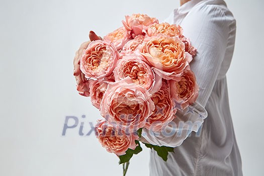 Girl with a bouquet of beautiful pink media roses on a gray background. Mother's Day, Valentine's Day Girl with a bouquet of beautiful pink media roses on a gray background. Mother's Day, Valentine's Day