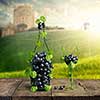 Bottle of Wine and a glass made by of grape leaves and a bunch of grapes on a wooden background with a blurred background view of the Castle, mill and the green lawn