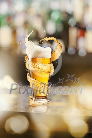 A cold glass of beer with beer foam and splash around on a wooden bar counter and blurred background with many bokeh A cold glass of beer with beer foam and splash around on a wooden bar counter and blurred background with many bokeh