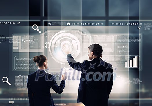 Rear view of businessman and businesswoman touching icon of digital screen Rear view of businessman and businesswoman touching icon of digital screen