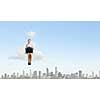 Young pretty businesswoman sitting on cloud high above city