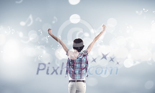 Rear view of young girl in casual wearing headphones Rear view of young girl in casual wearing headphones