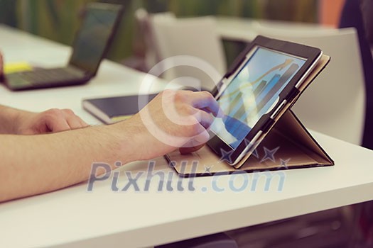 Closeup of mature hands holding tablet. Teacher with students in classroom Closeup of mature hands holding tablet. Teacher with students in classroom
