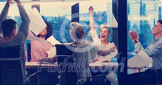 multiethnic Group of young business people throwing documents and looking happy while celebrating success at their working places in night office multiethnic Group of young business people throwing documents and looking happy while celebrating success at their working places in night office
