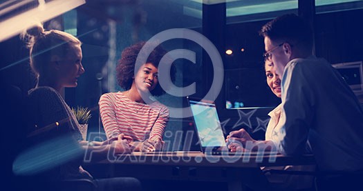 Multiethnic startup business team on meeting in modern night office interior brainstorming, working on laptop Multiethnic startup business team on meeting in modern night office interior brainstorming, working on laptop