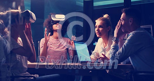 Multiethnic Business team using virtual reality headset in night office meeting Developers meeting with virtual reality simulator around table in creative office. Multiethnic Business team using virtual reality headset in night office meeting Developers meeting with virtual reality simulator around table in creative office.