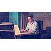 Young man working on laptop at night in dark office. The designer works in the later time.