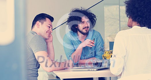 Multiethnic startup business team on meeting in modern bright office interior brainstorming, working on laptop and tablet computer