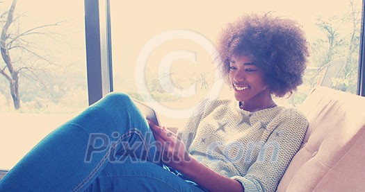 Young african american woman at home relaxing in her luxury lliving room reading a digital tablet PC surf internet and work Young african american woman at home relaxing in her luxury lliving room reading a digital tablet PC surf internet and work