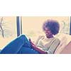 Young african american woman at home relaxing in her luxury lliving room reading a digital tablet PC surf internet and work