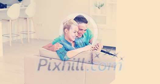 Young couple relaxing at luxurious home with tablet computers reading in the living room on the sofa couch. Young couple relaxing at luxurious home with tablet computers reading in the living room on the sofa couch.