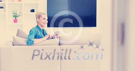 young happy woman on sofa using tablet computer at luxury home young happy woman on sofa using tablet computer at luxury home