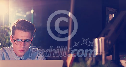 Young man working on computer at night in dark office. The designer works in the later time. Young man working on computer at night in dark office. The designer works in the later time.