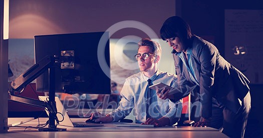 Two young designers are working on a new project in the night office using modern technology Two young designers are working on a new project in the night office using modern technology