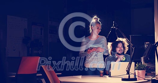 Two young designers are working on a new project in the night office using modern technology Two young designers are working on a new project in the night office using modern technology