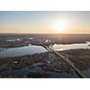 Aerial view of the bridge and the road over the Dnepr River over a green island in the middle of the river. City of Kiev at sunset, Ukraine.