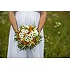 Beautiful bride with bouquet. Fashion brunette model outdoors. Portrait beauty model in white bridal dress holding flowers