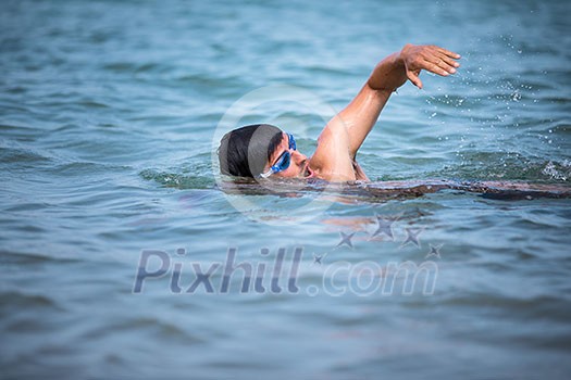 Triathlete man swimming freestyle crawl in ocean - Male triathlon swimmer training for a triathlon Triathlete man swimming freestyle crawl in ocean - Male triathlon swimmer training for a triathlon