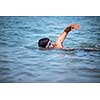 Triathlete man swimming freestyle crawl in ocean - Male triathlon swimmer training for a triathlon