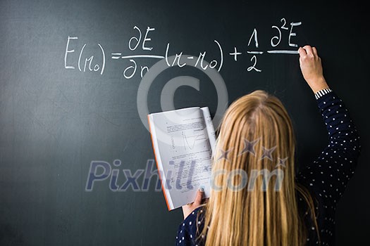Pretty, young college student writing on the chalkboard/blackboard during a math class (colort toned image; shallow DOF) Pretty, young college student writing on the chalkboard/blackboard during a math class (colort toned image; shallow DOF)