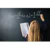 Pretty, young college student writing on the chalkboard/blackboard during a math class (colort toned image; shallow DOF)