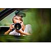 Female photographer/paparazzi taking pictures of a famous high-profile person from her car