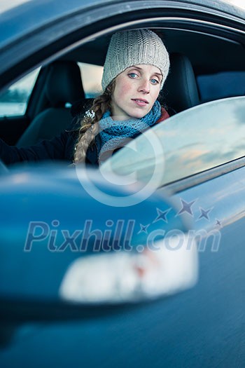 Woman driving a car - female driver at a wheel of a modern car, looking happy, smiling with a relaxed smile (shallow DOF; color toned image) Woman driving a car - female driver at a wheel of a modern car, looking happy, smiling with a relaxed smile (shallow DOF; color toned image)