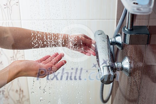 Hands of a young woman taking a hot shower at home Hands of a young woman taking a hot shower at home