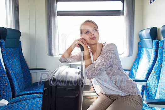Pretty young woman traveling on a train with her big trunk (color toned image) Pretty young woman traveling on a train with her big trunk (color toned image)