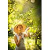 Pretty, young woman gardening in her garden, cutting branches, taking care of her lovely orchard