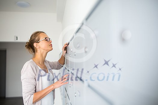 Pretty, young woman checking her mailbox for new letters Pretty, young woman checking her mailbox for new letters
