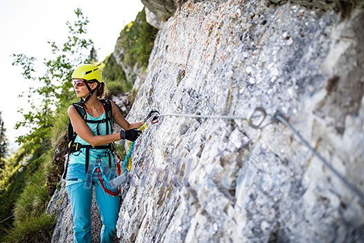 Pretty, female climber on a via ferrata - climbing on a rock in Swiss Alps Pretty, female climber on a via ferrata - climbing on a rock in Swiss Alps