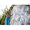 Pretty, female climber on a via ferrata -  climbing on a rock in Swiss Alps