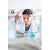 Young, female researcher carrying out experiments in a lab (shallow DOF; color toned image)