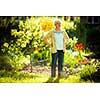 Senior woman doing some gardening in her lovely garden - watering the plants