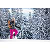 Pretty, young woman snowshoeing in high mountains, enjoying splendid winter weather with abundance of snow