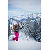 Pretty, young woman snowshoeing in high mountains, enjoying splendid winter weather with abundance of snow