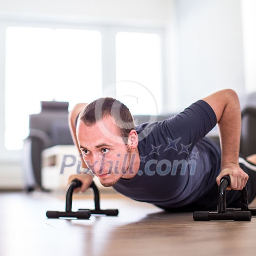 Handsome young man doing push-up at home, getting stronger each day using only his body weight Handsome young man doing push-up at home, getting stronger each day using only his body weight